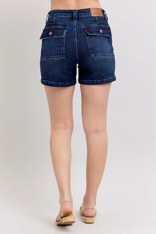 Back view of high-waisted dark wash denim shorts with flap pockets on a model