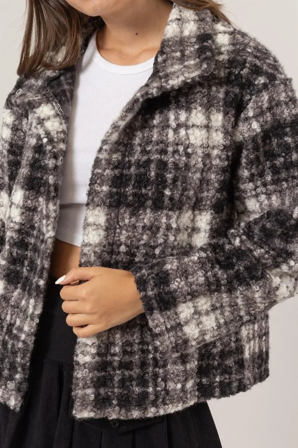 Woman wearing a boucle plaid jacket in black and white, styled with a white crop top