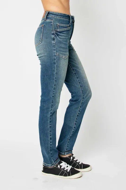 Woman wearing mid-rise blue skinny jeans and black sneakers, side view