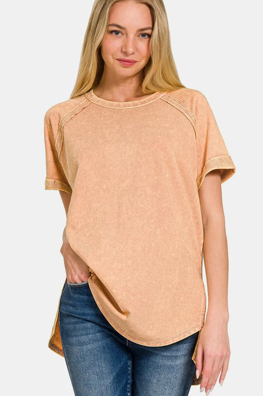 Woman wearing a peach-toned short sleeve relaxed t-shirt and blue jeans on white background