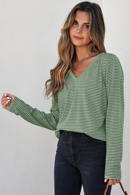 Woman wearing a green striped V-neck long sleeve top with black high-waisted jeans