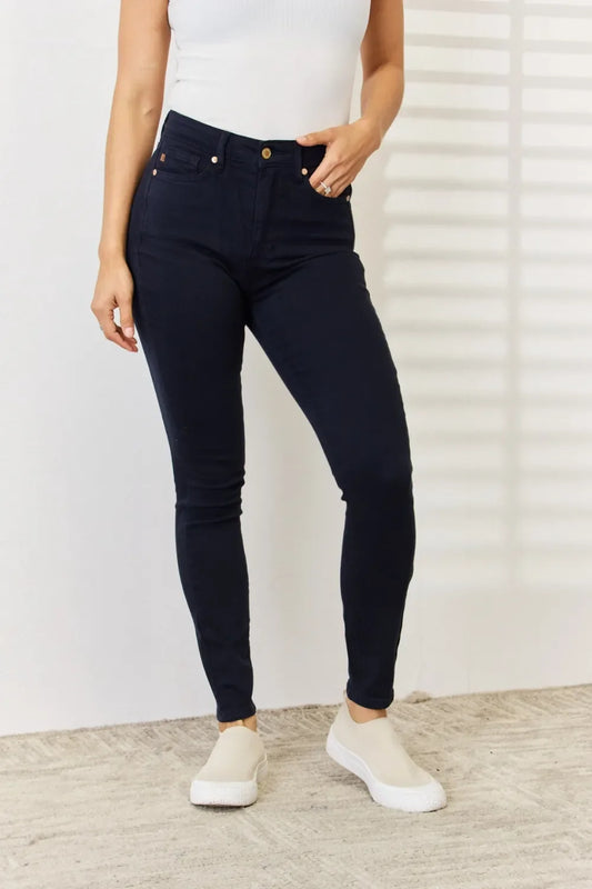 Woman wearing high-waisted dark skinny jeans and beige slip-on shoes on carpet