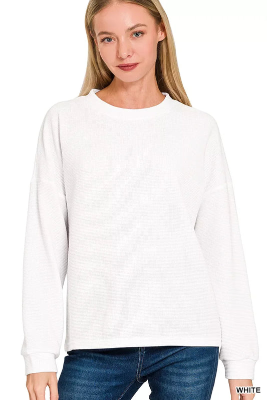 Woman wearing a relaxed-fit white long sleeve waffle knit sweater and blue jeans