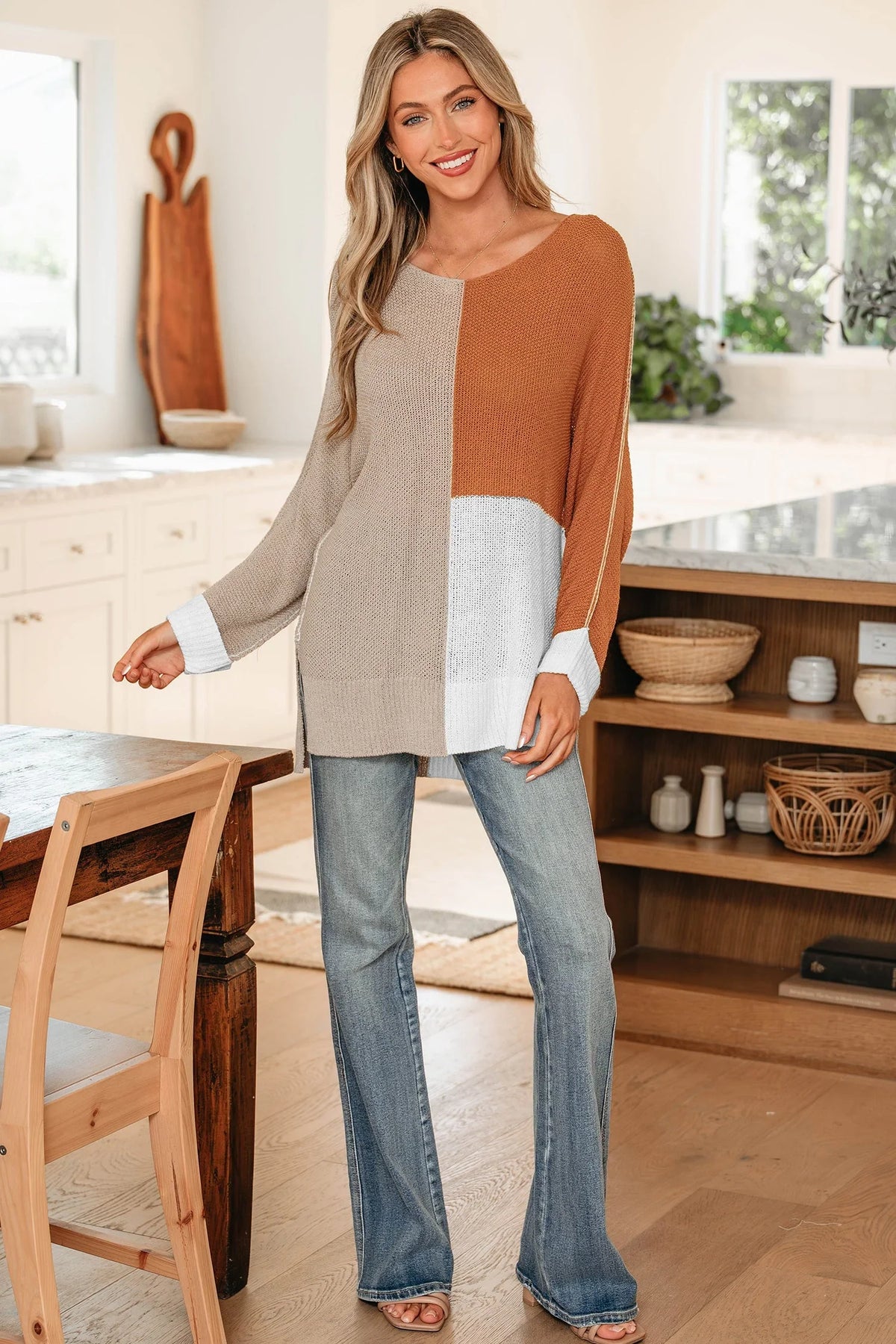 Woman wearing a colorblock knit sweater and blue jeans in a modern kitchen setting