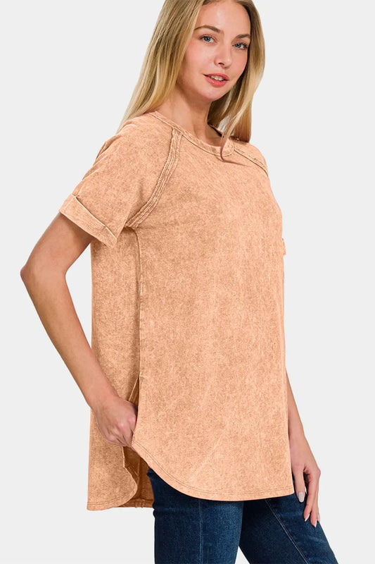 Woman wearing a relaxed-fit peach short sleeve top with rolled cuffs and blue jeans