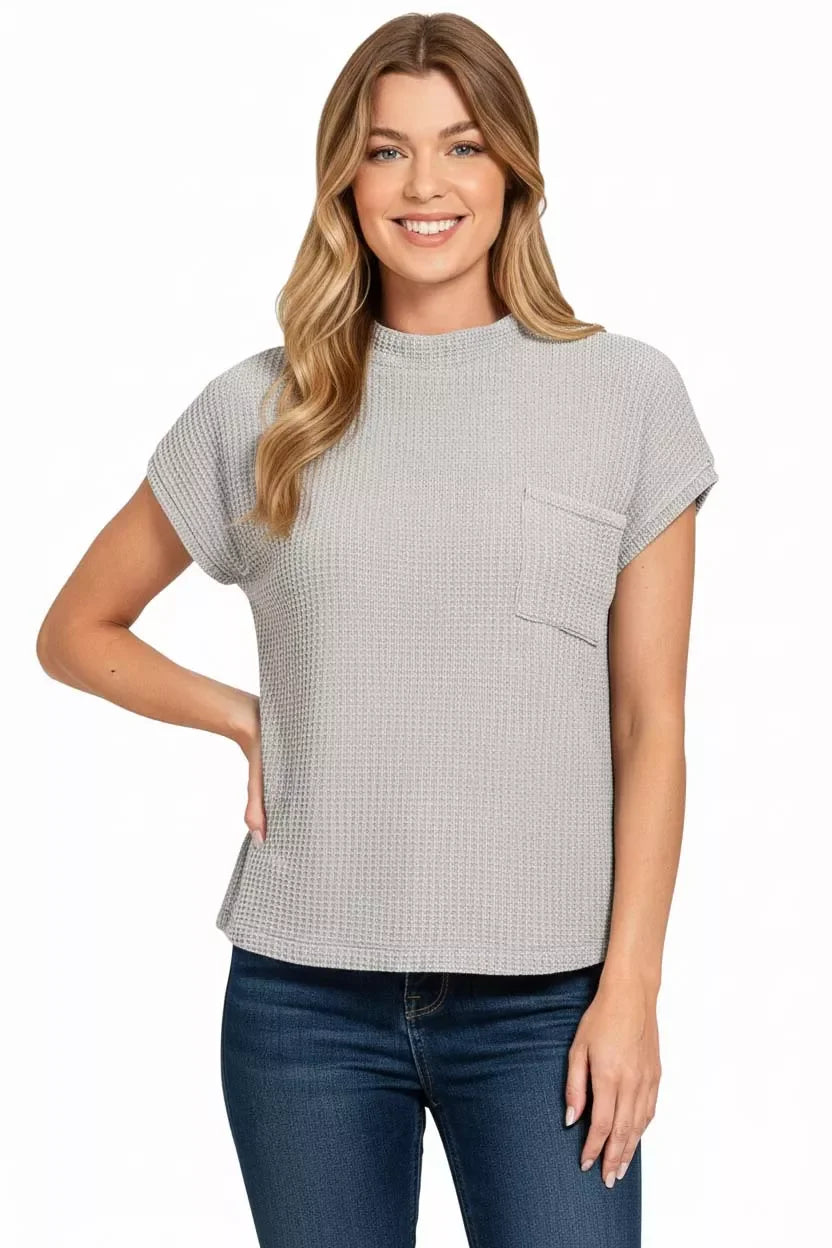 Woman wearing a textured short sleeve grey waffle knit top with chest pocket and blue jeans