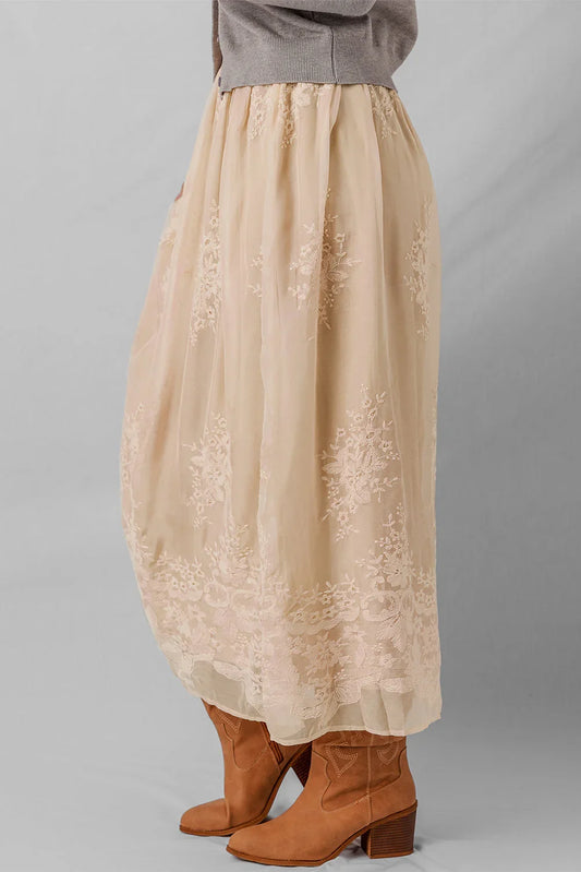 Beige embroidered tulle midi skirt paired with tan suede ankle boots, grey sweater above.