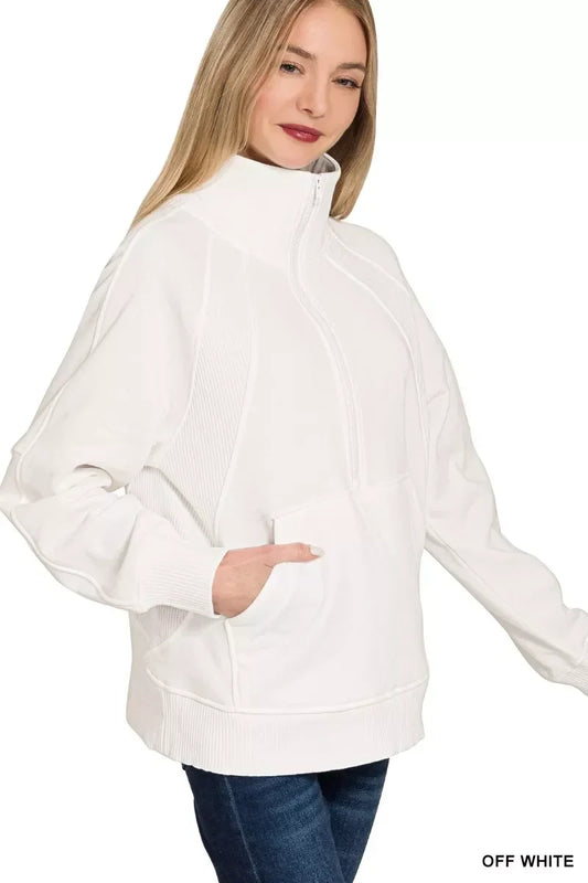 Woman wearing an off-white half-zip pullover sweater with front pocket and high collar