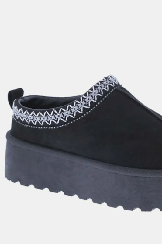 Black platform slip-on shoe with thick sole and white woven trim detail