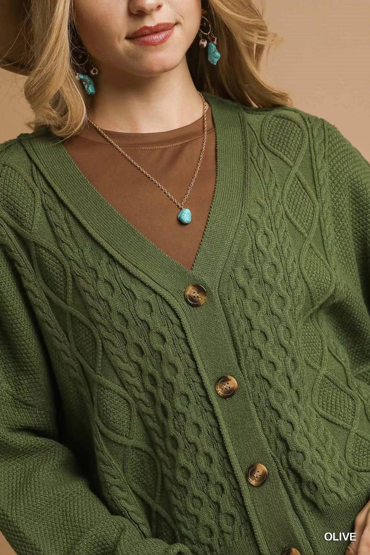 Woman wearing olive green cable knit cardigan with brown undershirt and turquoise jewelry.
