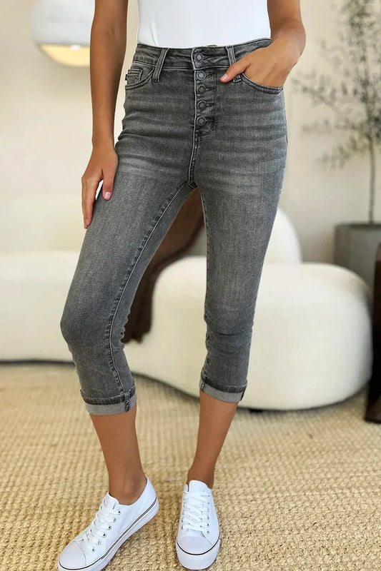 Woman wearing high-waisted grey cropped jeans with button fly and white sneakers