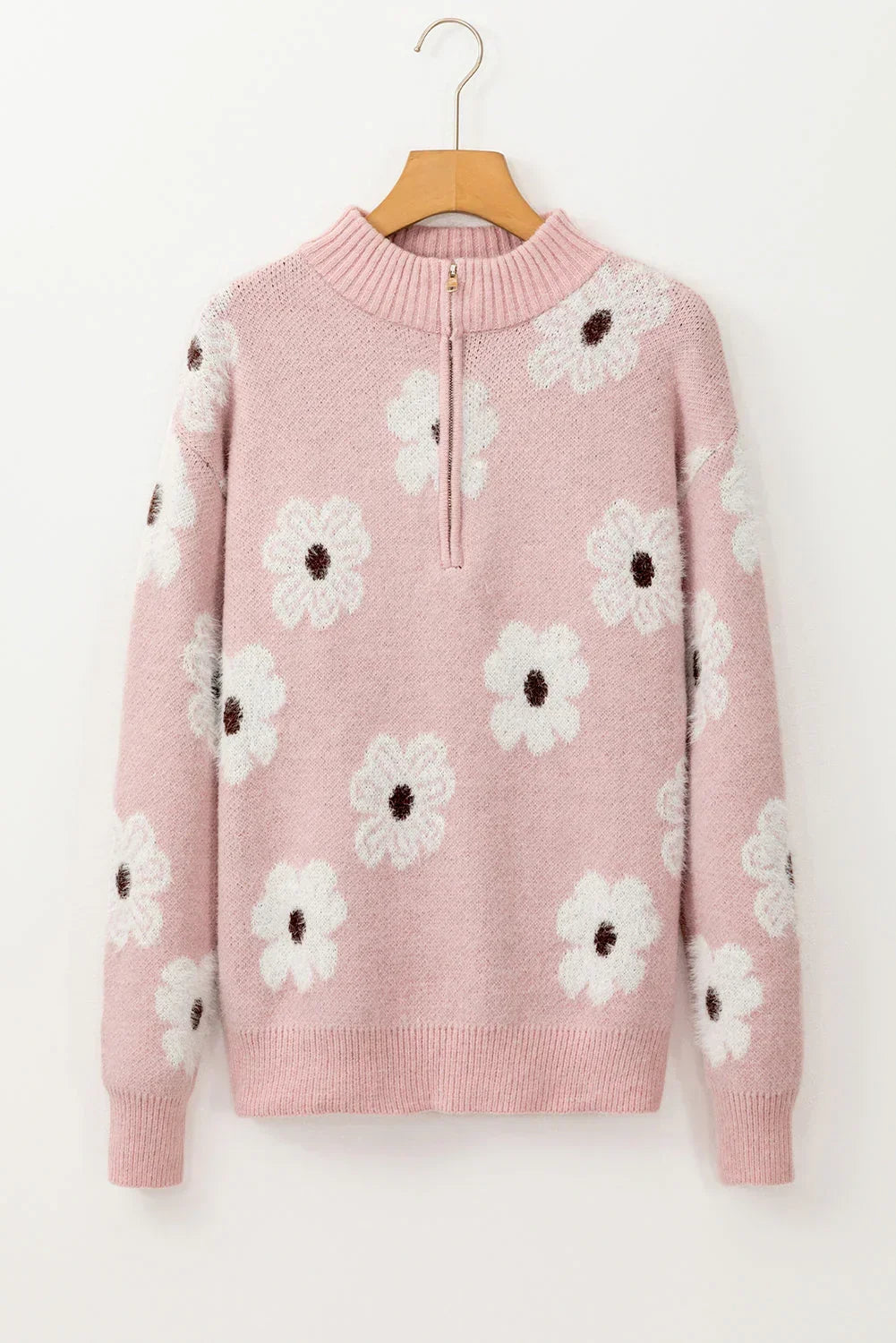 Pink knit sweater with white floral pattern and front zip collar, displayed on hanger