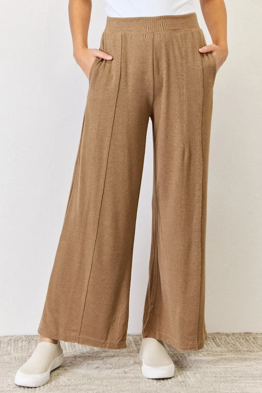 Woman wearing relaxed fit, wide leg brown knit pants with side pockets and white shoes