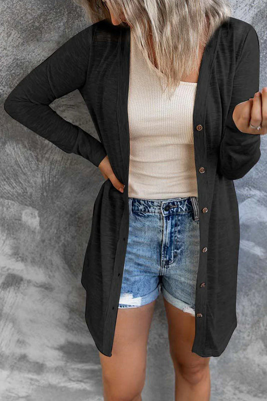 Woman wearing a black button-front cardigan, beige ribbed tank top, and denim shorts