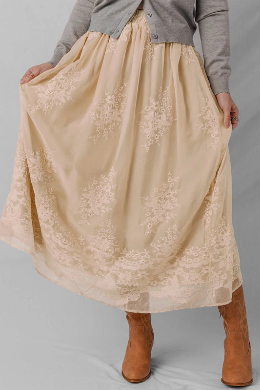 Woman wearing a beige embroidered tulle maxi skirt with a grey cardigan and suede boots