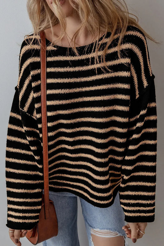 Woman wearing a black and beige striped knit sweater with relaxed fit and distressed jeans