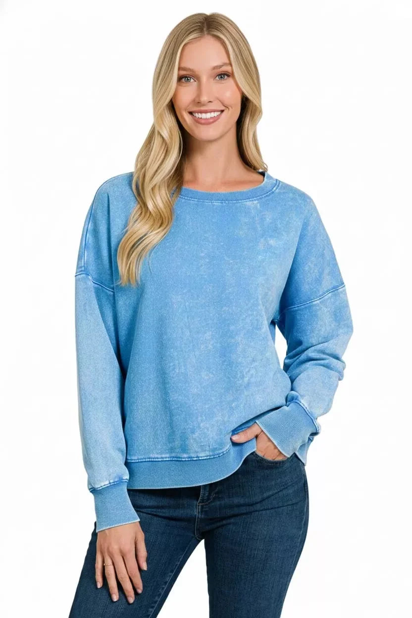 Woman wearing a relaxed fit light blue pullover sweatshirt with long sleeves and jeans.