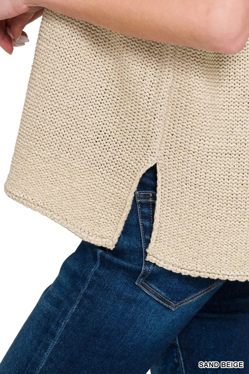 Close-up of sand beige knit sweater with side slit, paired with dark blue denim jeans.