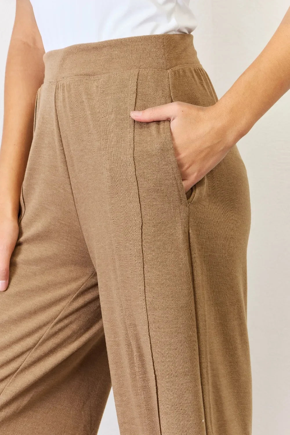 Woman wearing relaxed fit, high-waisted tan knit pants with side pockets