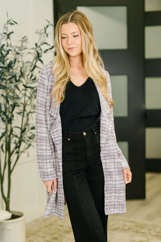 Woman wearing lavender ivory tweed midi blazer over black top and high-waisted black pants