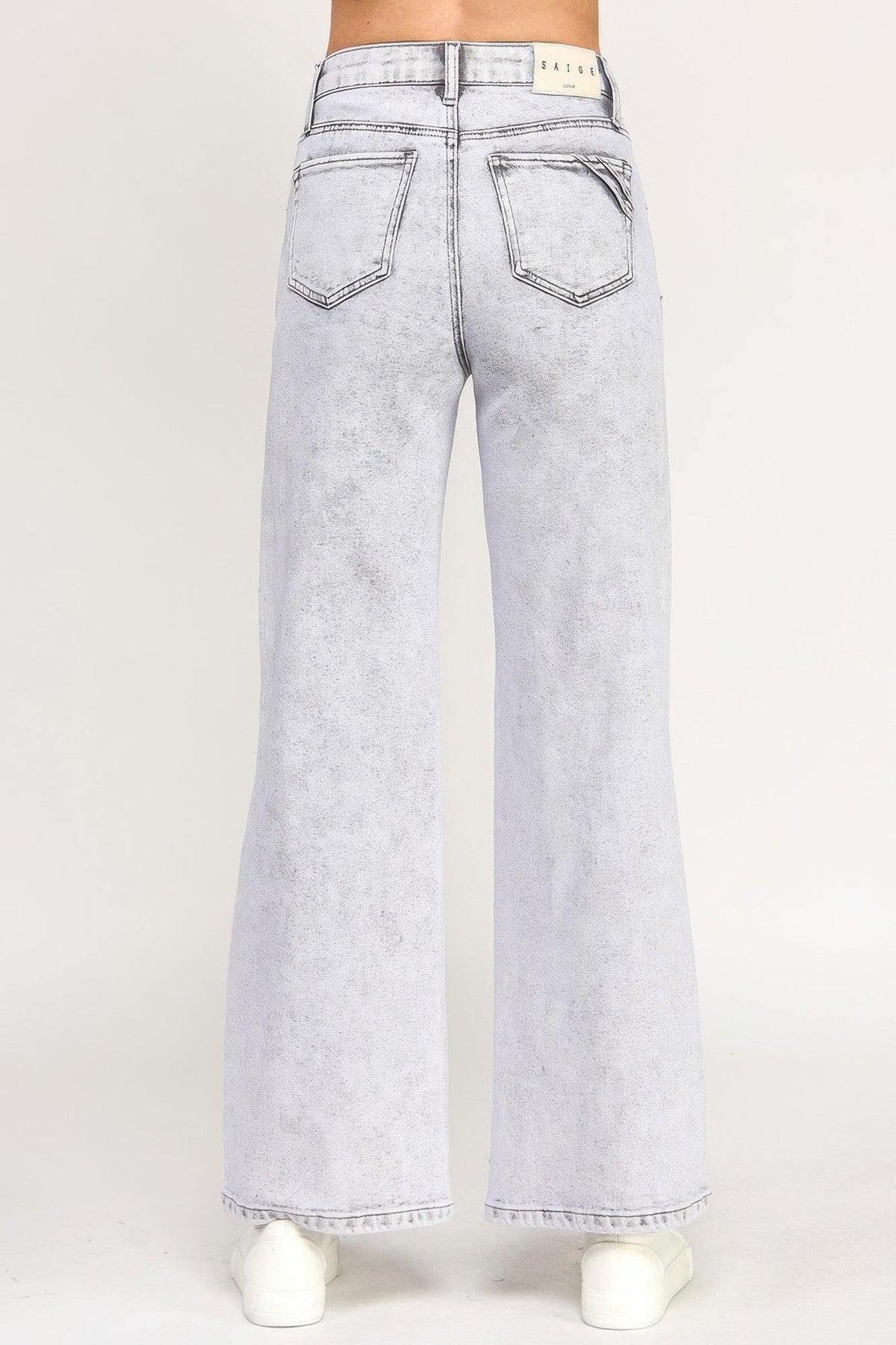 Back view of high-rise wide-leg light wash jeans with patch pockets, styled with white sneakers