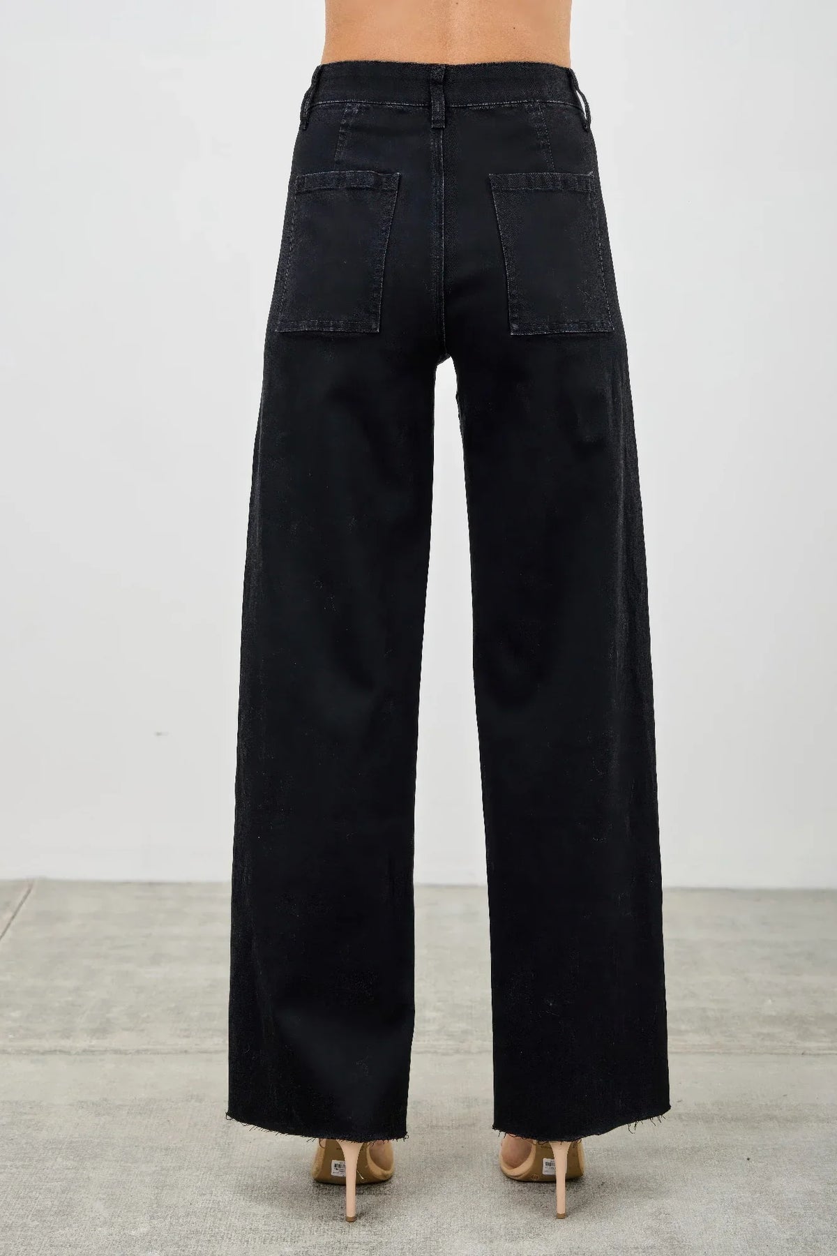 Back view of high-waisted black wide-leg jeans with rear patch pockets and raw hem