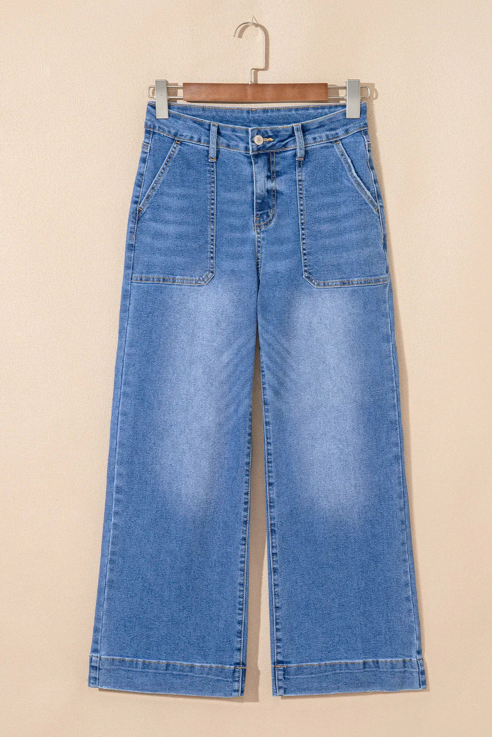 Wide-leg light blue denim jeans with large front pockets and high waist, hanging on a rack.