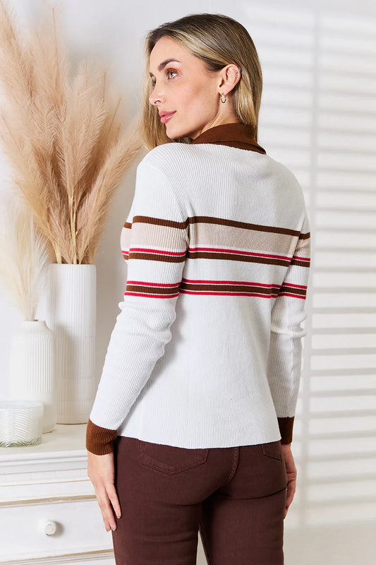 Woman wearing a white ribbed sweater with brown and red stripes and brown pants
