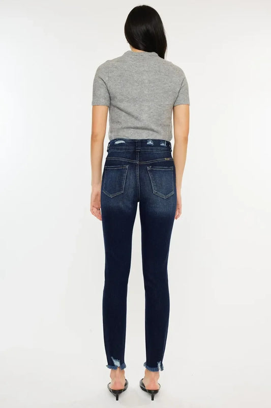 Woman in fitted dark wash skinny jeans with raw hem and short-sleeve gray sweater, back view.