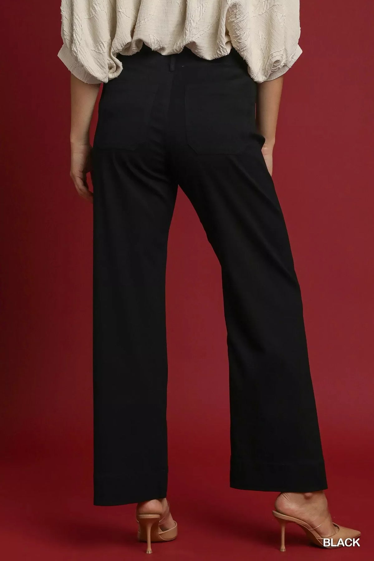 Back view of woman wearing black high-waisted wide-leg pants and nude heels