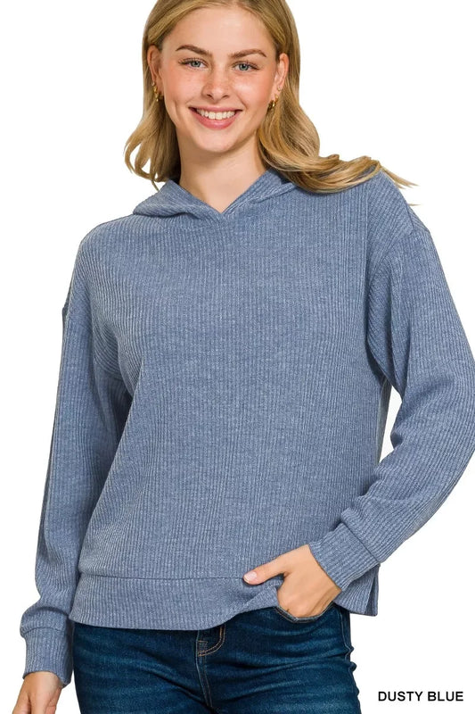 Woman wearing a dusty blue ribbed knit hoodie with relaxed fit and long sleeves.