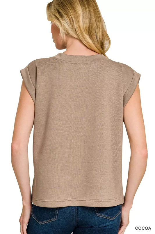 Back view of woman wearing a loose-fit cocoa short sleeve top with rolled cuffs and blue jeans