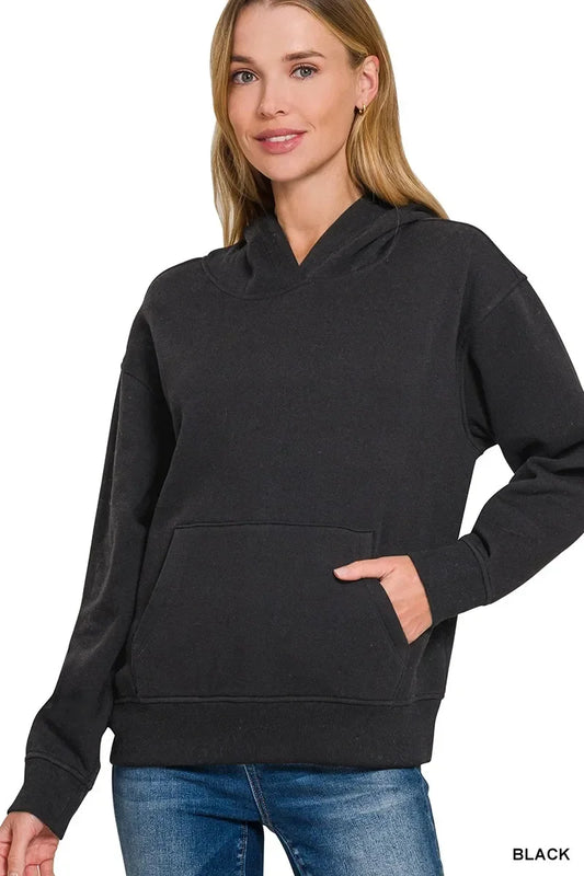 Woman wearing black relaxed fit hoodie with kangaroo pocket and blue jeans