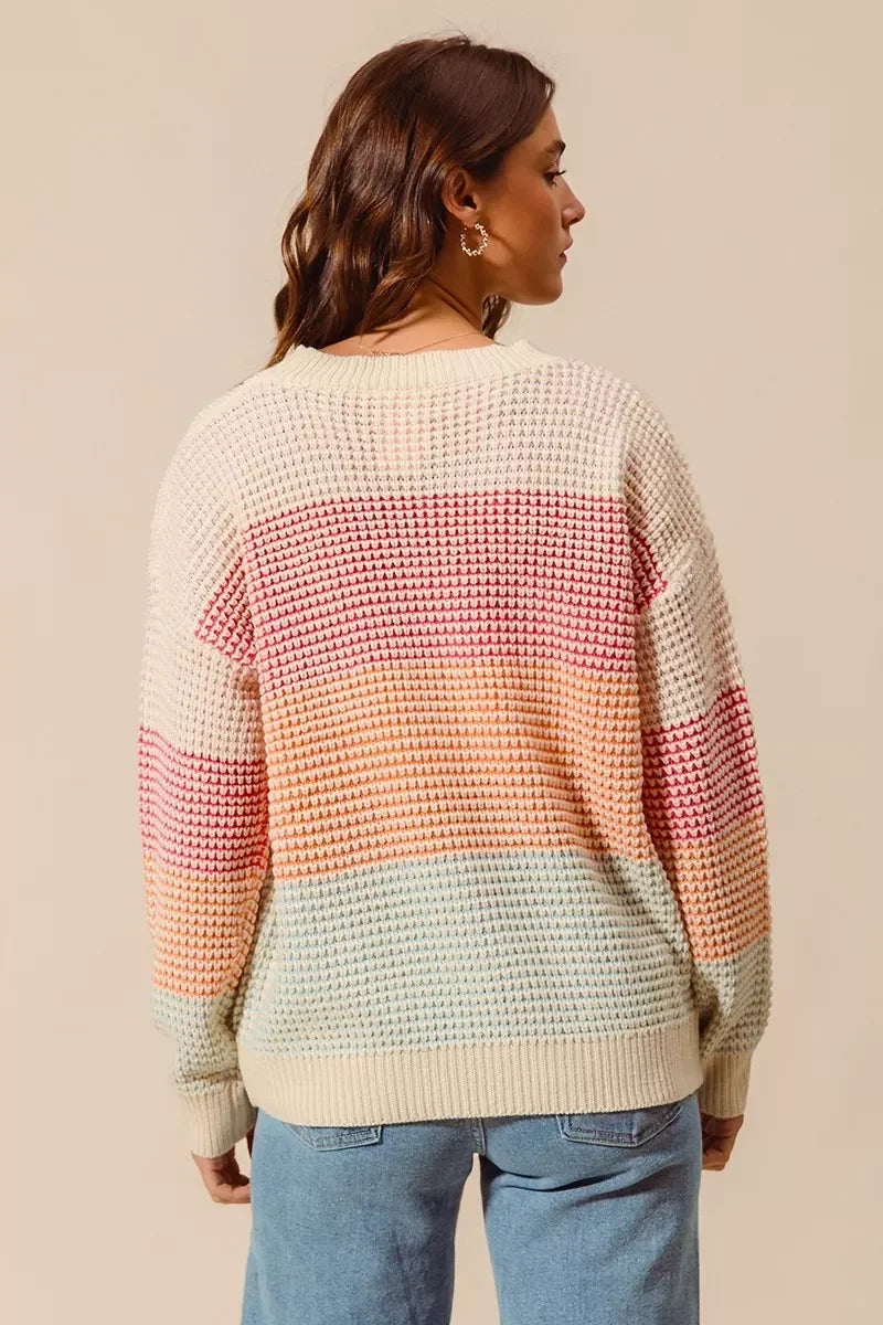 Back view of woman in a pastel striped knit sweater and light blue jeans