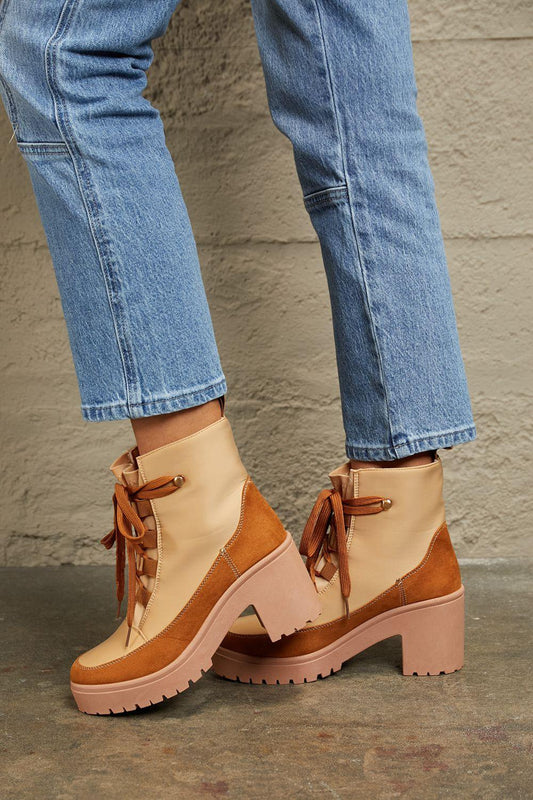 Tan and brown lace-up platform boots paired with cropped blue jeans on concrete floor