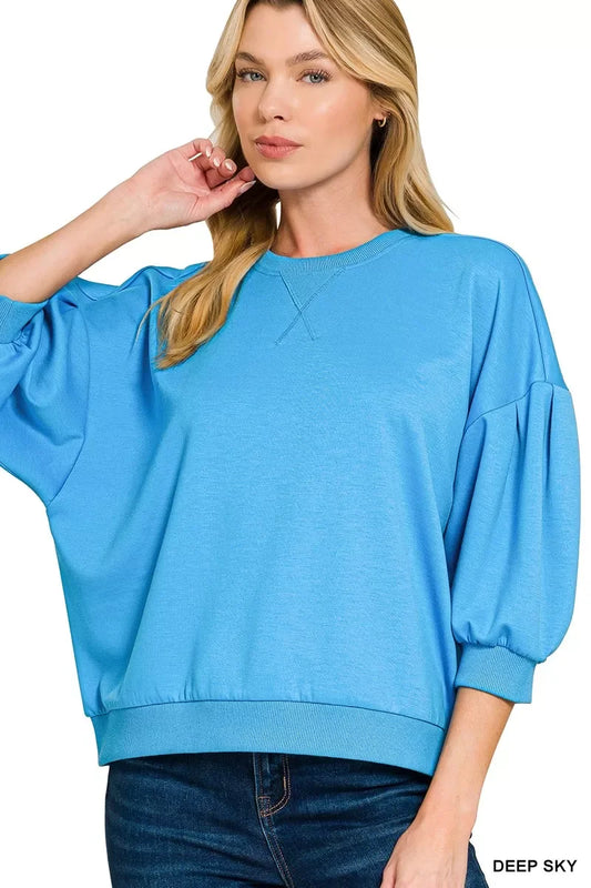 Woman wearing a loose fit, deep sky blue pullover with balloon sleeves and relaxed silhouette.