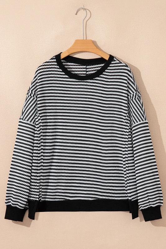 Black and white striped knit sweater with long sleeves and relaxed fit on a hanger