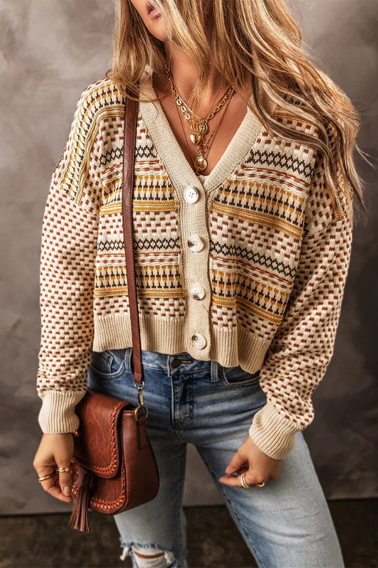 Woman wearing a patterned knit cardigan with large buttons, blue jeans, and a brown crossbody bag.
