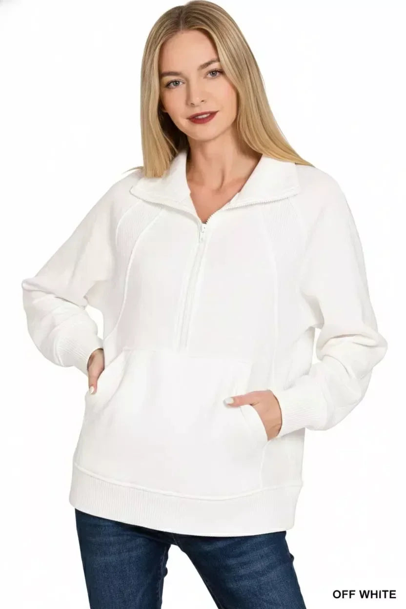 Woman wearing off-white half-zip pullover sweater with front pocket and casual jeans