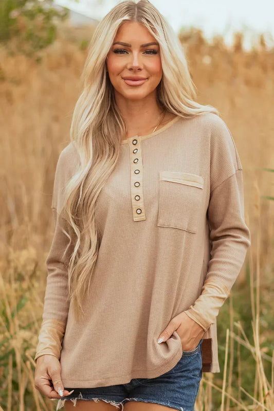 Woman wearing a beige waffle knit long sleeve henley top with front pocket outdoors