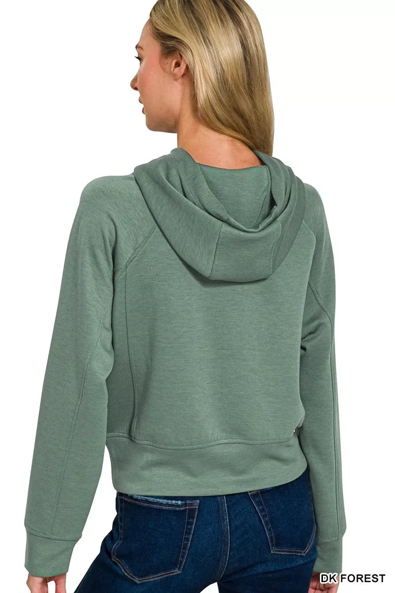Woman wearing a dark green hooded sweatshirt with relaxed fit and blue jeans, back view.