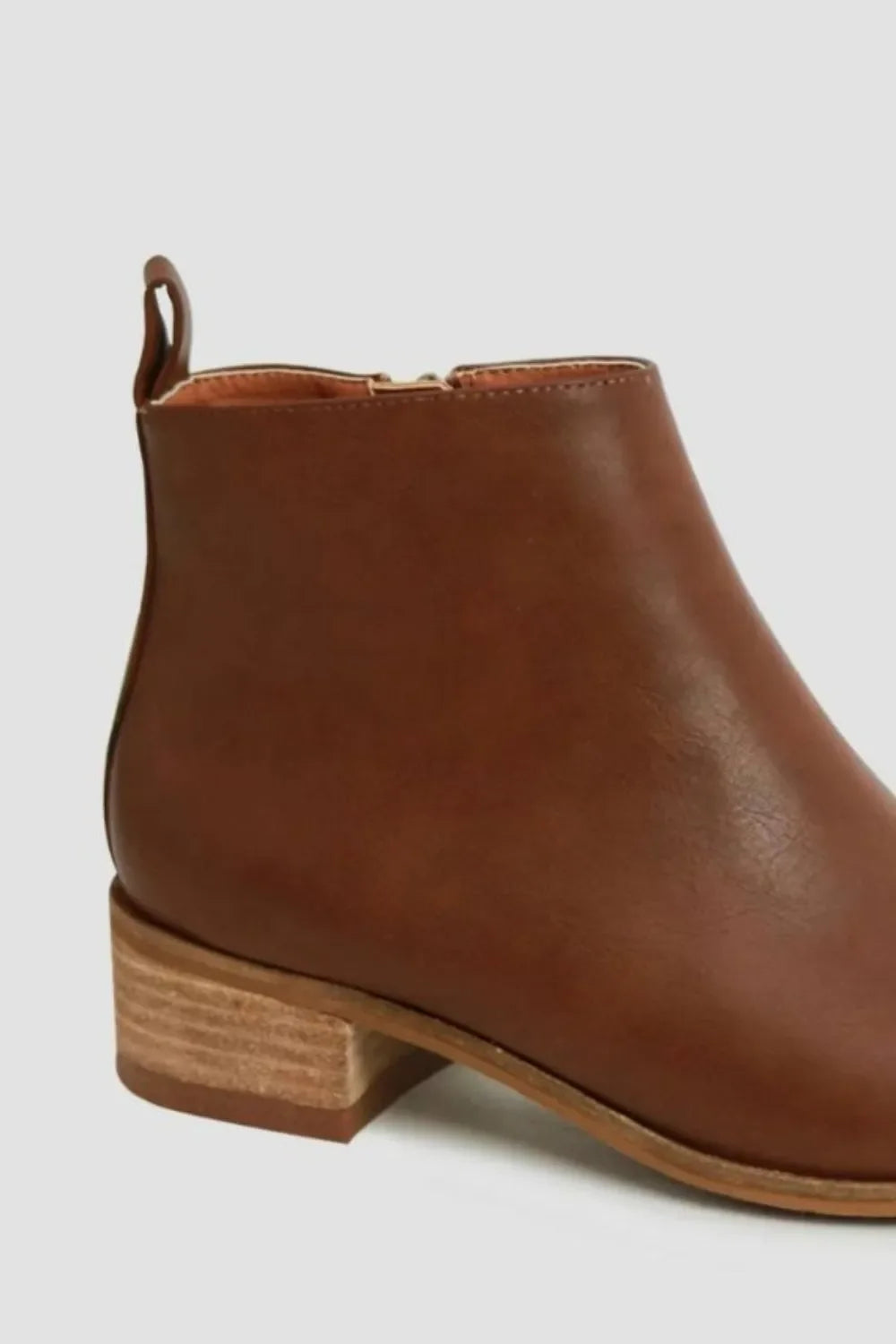 Side view of brown leather ankle boot with low stacked heel on light background