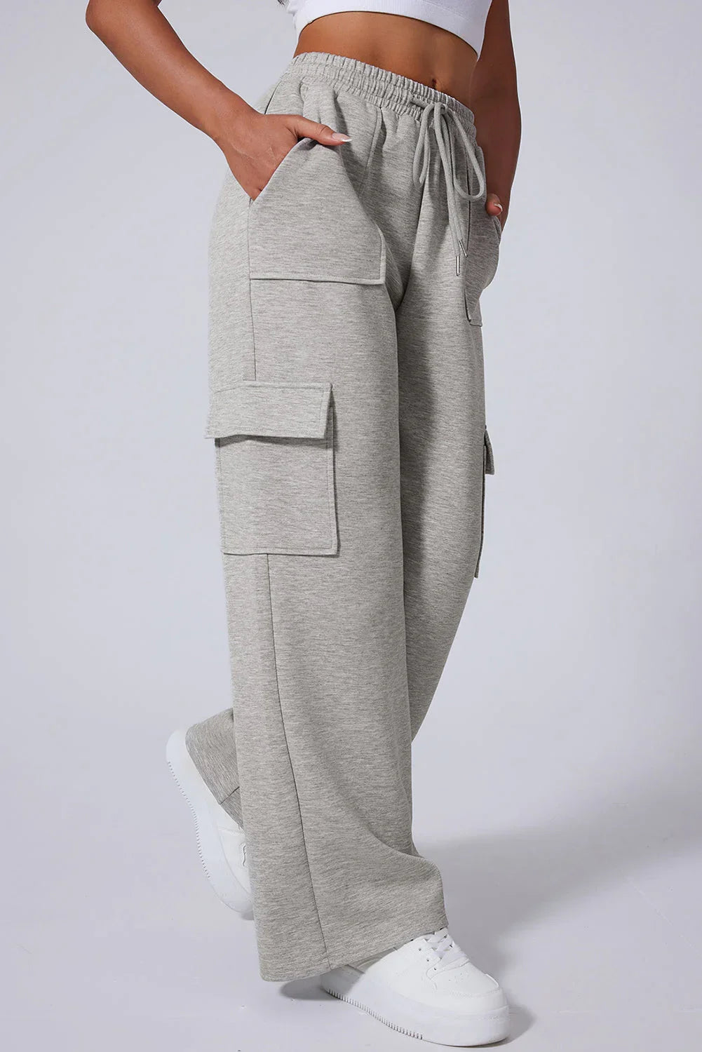 Light grey wide-leg cargo sweatpants with flap pockets, elastic waist, and white sneakers