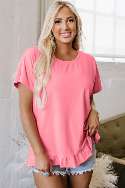 Woman wearing a bright pink ruffle hem blouse with light denim shorts indoors