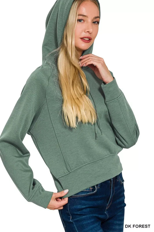 Woman wearing dark green hooded sweatshirt with relaxed fit and blue jeans