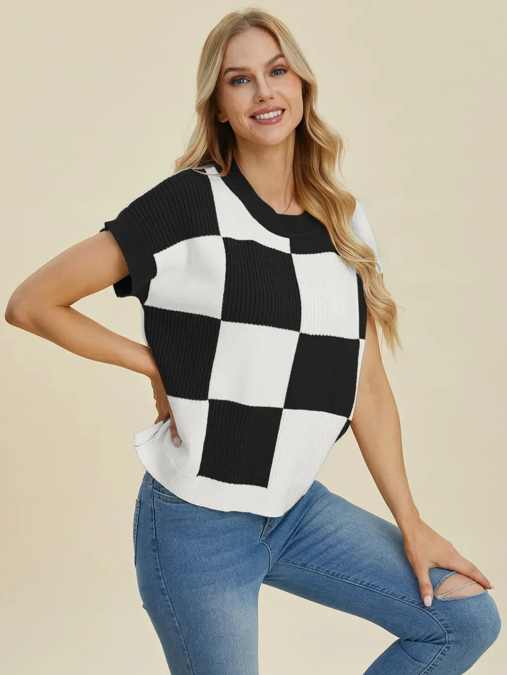 Woman wearing a black and white checkered knit top with short sleeves and blue jeans