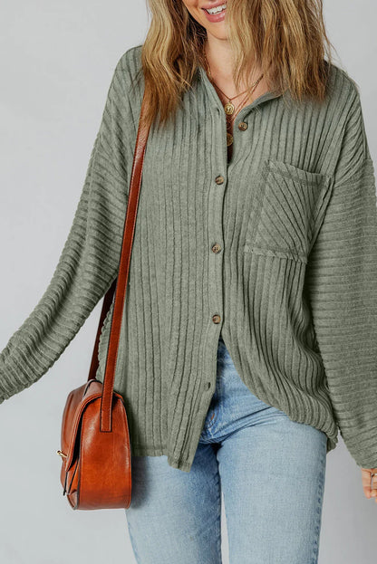 Woman wearing a ribbed sage green button-up shirt with blue jeans and brown leather handbag
