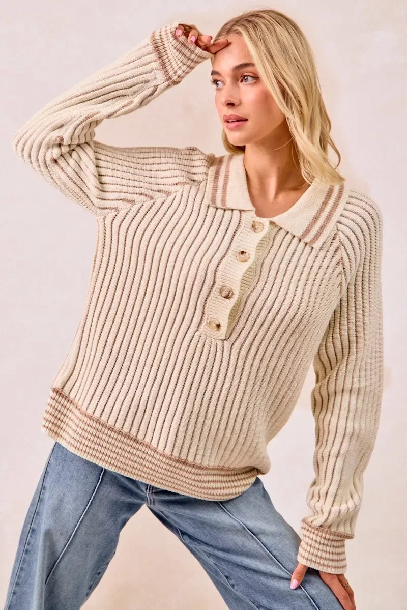 Woman wearing a cream ribbed knit sweater with collar and button detail, paired with jeans.