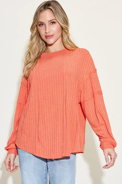 Woman wearing a relaxed fit long sleeve orange ribbed top and light wash jeans