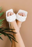Woman wearing white braided slide sandals with square toe, neutral background